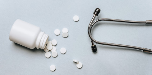 White pills, stethoscope on the doctor's table. Medicine concept. Research on prescribing the dose of medicinal products. Health care or illness. Tablet or drug in hospital or pharmacy.
