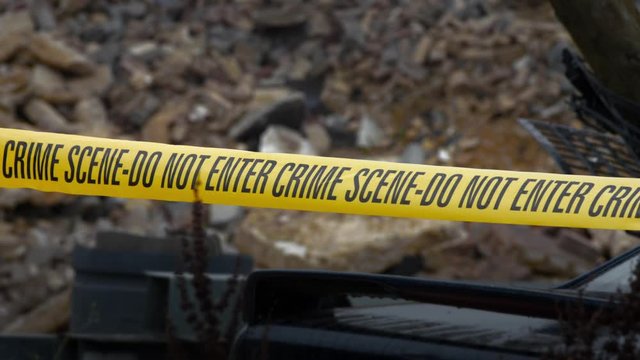 Police Crime Scene Cordon Tape Around Junkyard Car.  There is an overcast sky and light rainfall. Suggestive of the scene of a murder or hiding of a body.