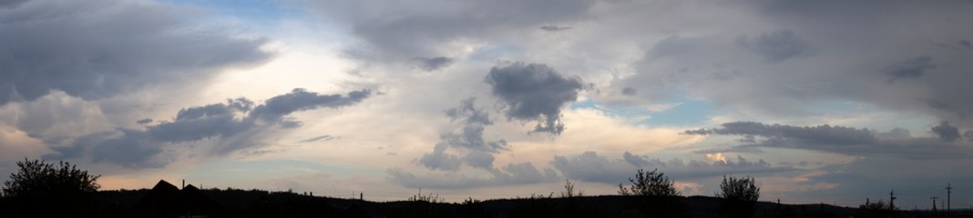 Storm clouds against a blue sky. The sun is hidden. Panorama. Tragic gloomy sky. Fantastic skies on the planet earth. Twilight, nightfall.