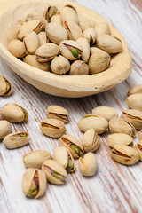 Pistachio nuts in wood spoon on wood background.