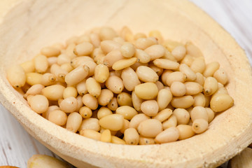 Pine nuts in a wooden spoon on a wooden background.