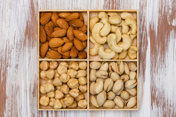 Mix of four different nuts in a wooden box on table. High quality photo. View from above.