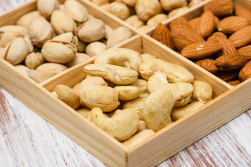 Close-up of cashew nuts in a wooden box. Assortment of nuts in the background.