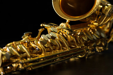 close up on alto saxophone details, black background, short depth of field.