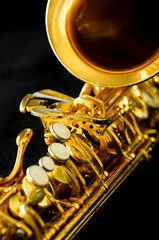 Obraz na płótnie Canvas close up on alto saxophone details, black background, short depth of field.