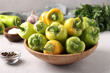 Organic bell peppers in a wooden plate on light gray background.