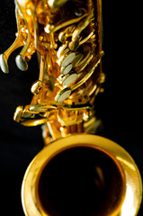 close up on alto saxophone details, black background, short depth of field.