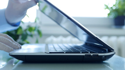 Closeup Image with Hands Wearing Protective Gloves Using the Laptop Keypad