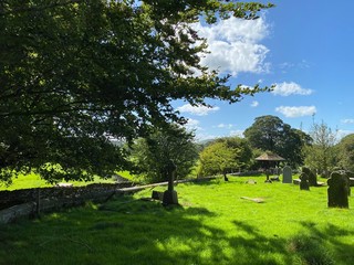 A small country graveyard, with trees, gravestones, grass, and sunlight in, Rylstone, Skipton, UK