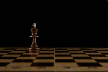 concept of loneliness. chess king is on chessboard on dark background with copy space