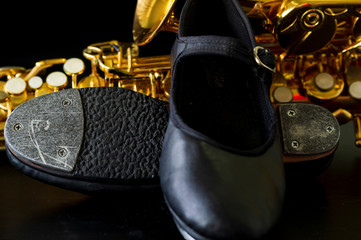 close up on tap shoe, defocused saxophone background, short depth of field.