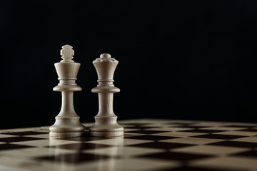 chess king and queen on chessboard on black background