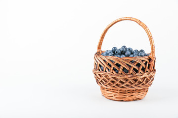 Fototapeta na wymiar blueberry berries in wicker basket on white background with copy space