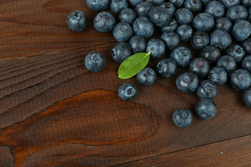 blueberry berries with green leaves on dark wooden background top view with copy space