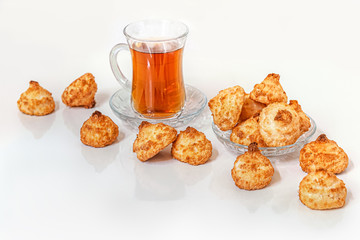 homemade flavored coconut cookies and a cup of hot tea on a light glossy surface