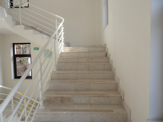 Light marble steps with white railings, white walls and windows with dark frames
