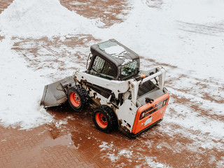 Orange and white tractor clearing snow in the square