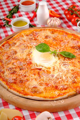 Pizza Carbonara with bacon, egg, parmesan cheese, fresh basil and tomatoes sauce on a wooden board, rustic village background, top view. European and 