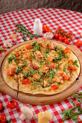 Pizza with seafood, mozzarella, mussels, octopus, squid, salmon, shrimp, cheeseand, fresh rucola and tomatoes sauce, served on a wooden board for a dinner in italian restaurant background, top view. 