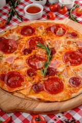 Neapolitan Pepperoni pizza with sausage, salami, cheese, rosemary and tomatoes sauce, served on a wooden board for a dinner in italian restaurant background, top view. Italy food.
