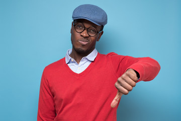 African man giving thumbs down gesture, looking with negative facial expression