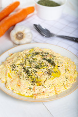 Fresh carrot salad with garlic yogurt in dish on wooden background.