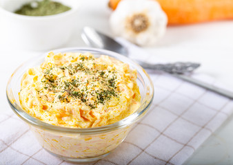 Fresh carrot salad with garlic yogurt in bowl on wooden background.