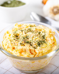 Fresh carrot salad with garlic yogurt in bowl on wooden background.