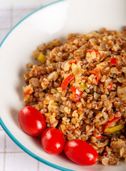 Buckwheat pilaf (pilav) with vegetable in dish on wooden background.