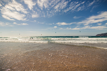 Guincho beach sea with surfers doing kitesurf and with the blue sky in the background, Cascais, Portugal