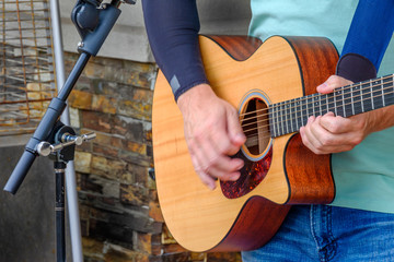 Guitar player playing a six string acoustic guitar with red iridescent pic guard. Hand motion blur captures the action.