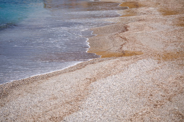 The beach of the Mediterranean coast with waves of azure water. Summer sea breeze
