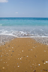 The beach of the Mediterranean coast with waves of azure water. Summer sea breeze