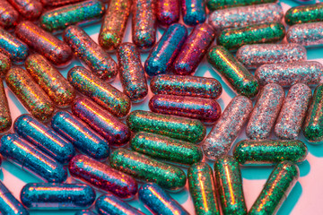 Creative concept with many colorful glitter pills scattered, lying randomly on pastel pink background. Minimal style, art concept