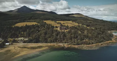Foto op Canvas Scotland's ocean coast landscape aerial view: forests, valleys, hills. Brodick castle - historical ancient building in Arran Island. Road with riding cars shot © Goinyk
