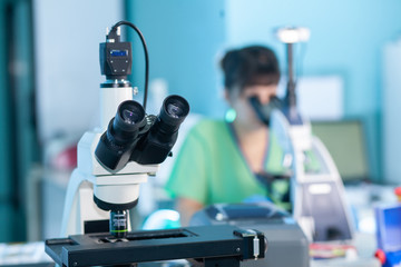 Female professional in uniform. Work with a light microscope in a research laboratory, testing...