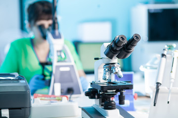 Female professional in uniform. Work with a light microscope in a research laboratory, testing...