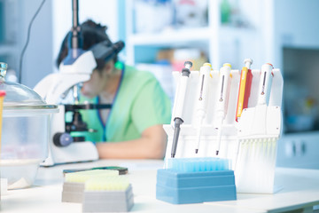 Female professional in uniform. Work with a light microscope in a research laboratory, testing...