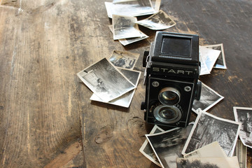 Polski powojenny aparat fotograficzny, obok rozrzucone czarno-białe zdjęcia