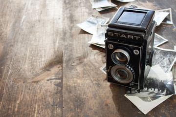 Polski powojenny aparat fotograficzny, obok rozrzucone czarno-białe zdjęcia