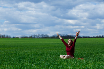 Young successful woman is sitting on green grass with a laptop in her hands. Rest after a good working day. Work on the nature. Student girl working in a secluded place. Workplace in nature