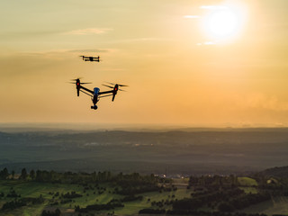 lecące drony na tle zachodzącego słońca