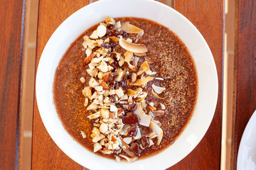 Breakfast bowl with quinoa, banana, coconut, cocoa, walnuts served on wooden table
