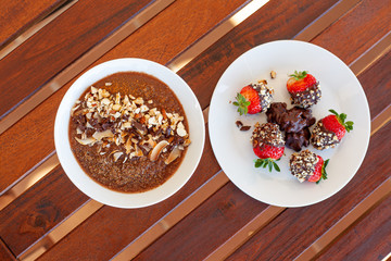 Breakfast bowl with quinoa, banana, coconut, cocoa, walnuts served on wooden table