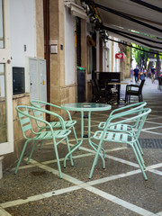 Terraza de una cafetería con mesas y sillas blancas vacía 