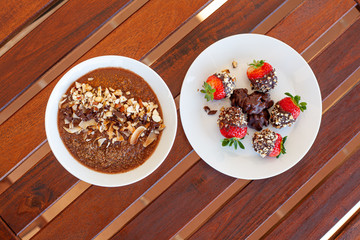 Breakfast bowl with quinoa, banana, coconut, cocoa, walnuts served on wooden table