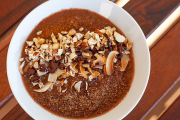 Breakfast bowl with quinoa, banana, coconut, cocoa, walnuts served on wooden table