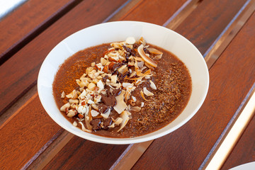 Breakfast bowl with quinoa, banana, coconut, cocoa, walnuts served on wooden table