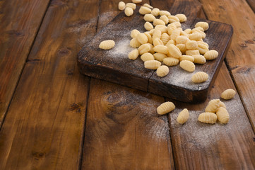 Gnocchi with potatoes. Traditional italian food from Rome, Sardinia, south of italy. Homemade gnocchi with parmesan, egg, cornmeal (semolina). On a wooden table. High quality photo. Above. Copy space 