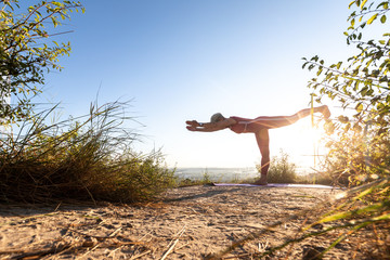 Woman yoga master doing at sunrise exercise in position warrior